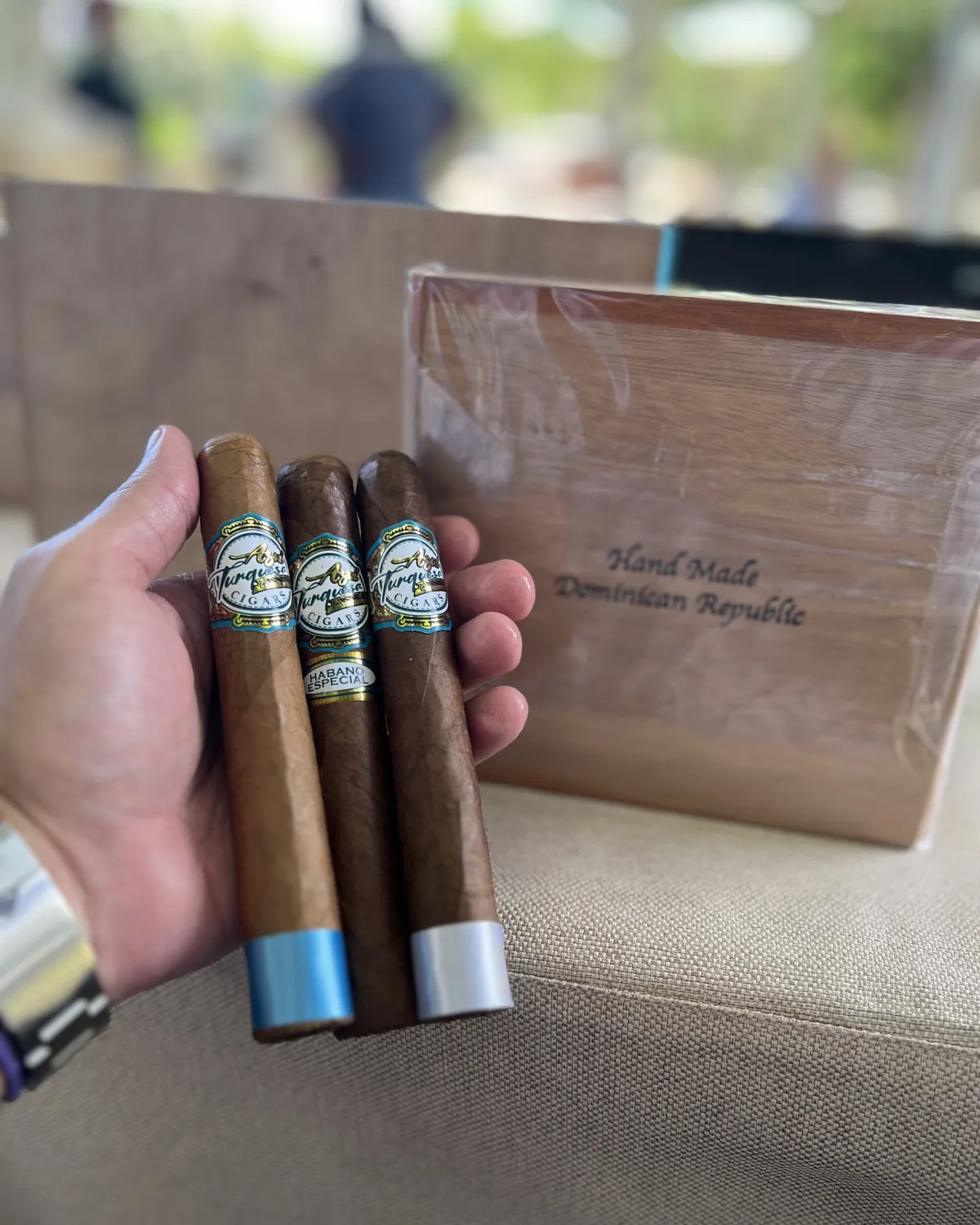 Tres puros Azul Turquesa sostenidos en la mano junto a una caja de madera